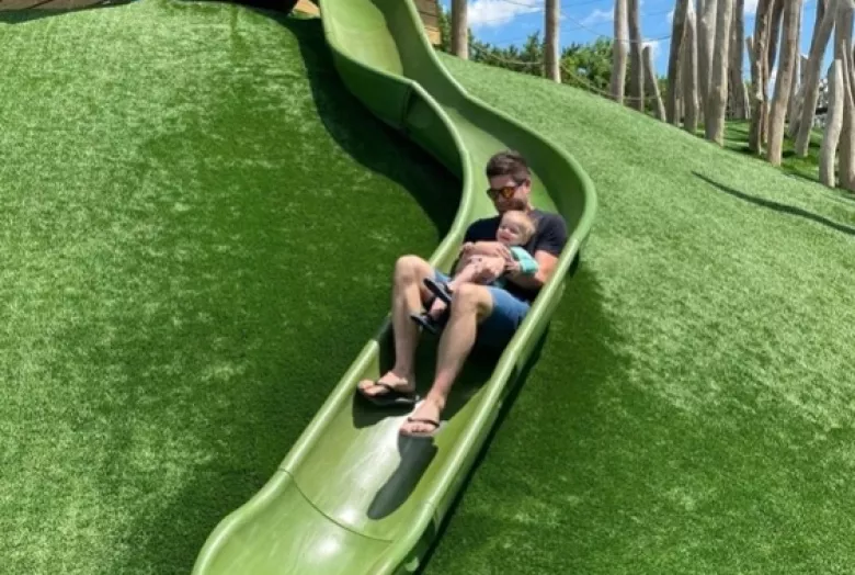 Father and child sliding down a slide together